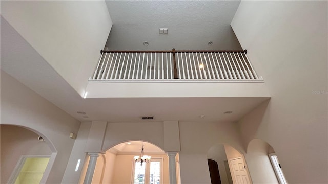 staircase featuring ornate columns, an inviting chandelier, ornamental molding, and a towering ceiling