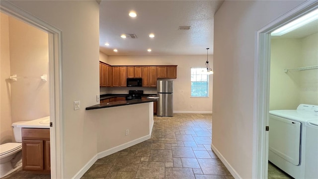 kitchen with pendant lighting, black appliances, and washer and clothes dryer