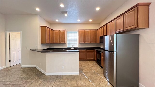 kitchen with black appliances, kitchen peninsula, and sink