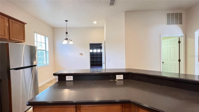 kitchen with stainless steel refrigerator, a textured ceiling, and a chandelier