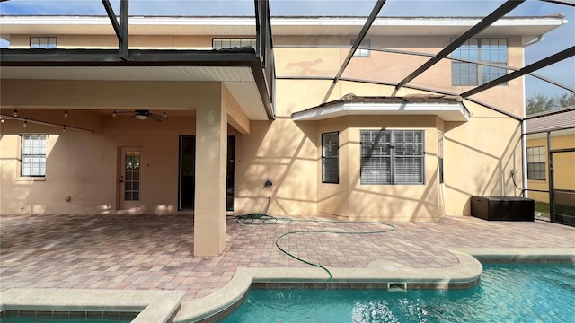 rear view of property featuring a patio, ceiling fan, and glass enclosure