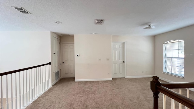 unfurnished bedroom with light colored carpet, a textured ceiling, and a closet