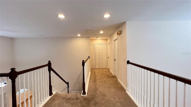 hall featuring a textured ceiling and carpet floors