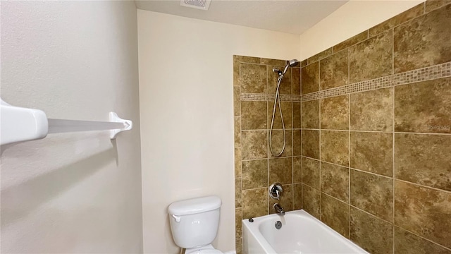 bathroom with tiled shower / bath combo and toilet