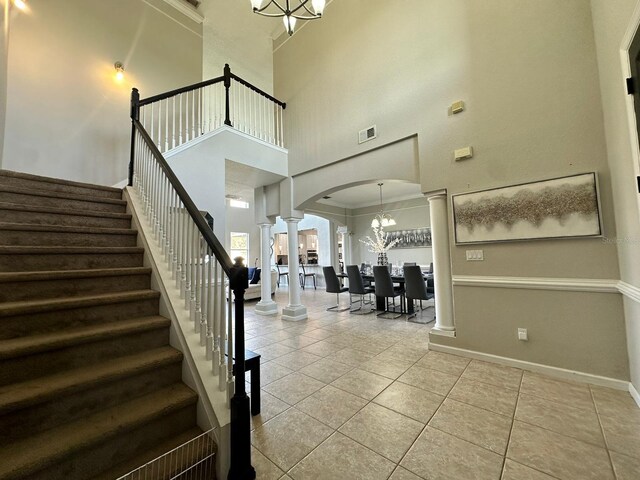 2321 Hinsdale Dr, Kissimmee, FL 34741 - stairs featuring ornate columns, a chandelier, arched walkways, a towering ceiling, and tile patterned floors