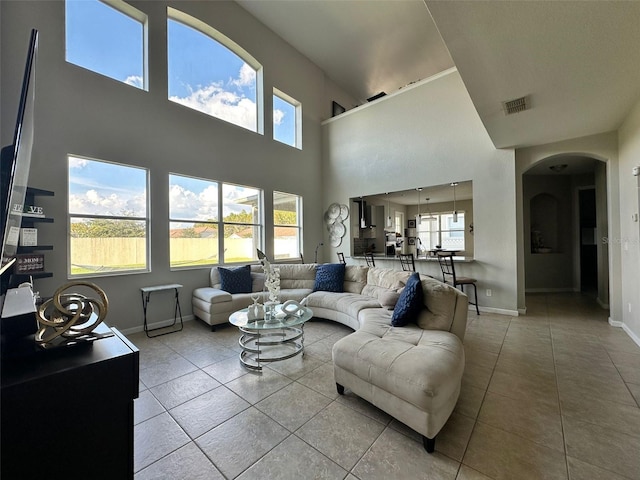 tiled living room featuring a towering ceiling and plenty of natural light