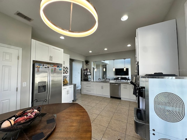 kitchen with sink, kitchen peninsula, white cabinetry, appliances with stainless steel finishes, and light tile patterned floors