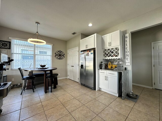 2321 Hinsdale Dr, Kissimmee, FL 34741 - kitchen with stainless steel fridge, tasteful backsplash, white cabinets, light tile patterned floors, and a textured ceiling