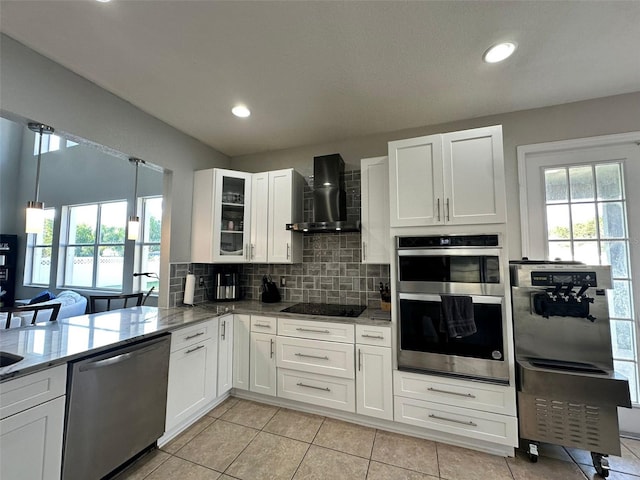 kitchen featuring white cabinets, stone countertops, wall chimney exhaust hood, backsplash, and stainless steel appliances