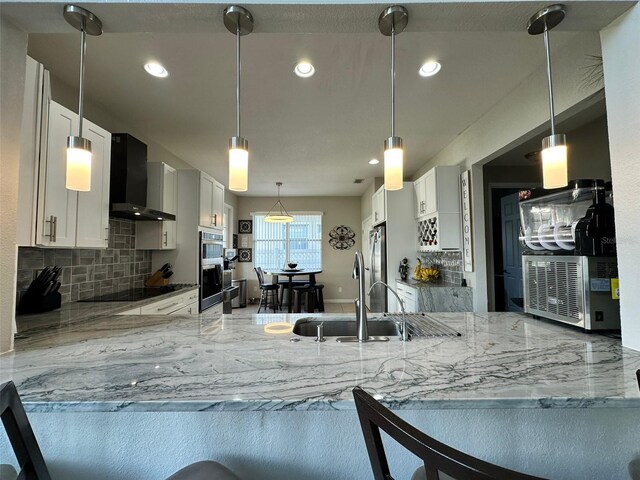 2321 Hinsdale Dr, Kissimmee, FL 34741 - kitchen with wall chimney exhaust hood, light stone counters, tasteful backsplash, appliances with stainless steel finishes, and recessed lighting