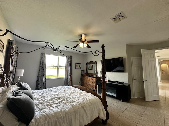 tiled bedroom featuring ceiling fan and a textured ceiling