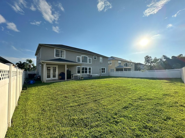 back of property with french doors, a patio, and a yard