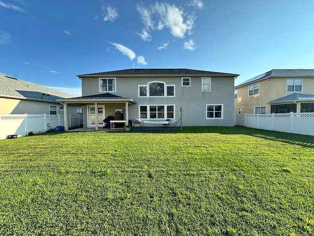 rear view of property featuring a lawn and a patio area