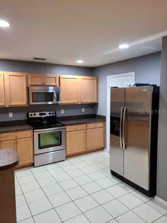 kitchen featuring dark countertops, appliances with stainless steel finishes, light tile patterned floors, and recessed lighting