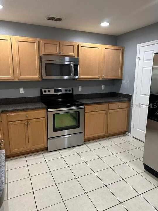 kitchen featuring visible vents, dark countertops, recessed lighting, appliances with stainless steel finishes, and light tile patterned floors
