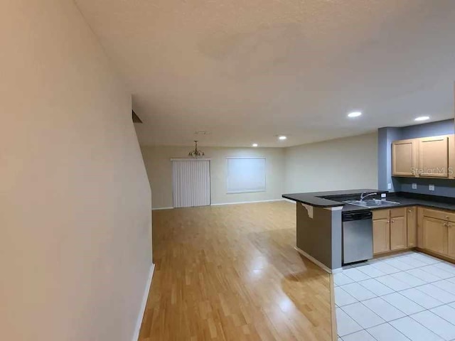 kitchen featuring a peninsula, dark countertops, open floor plan, light wood finished floors, and dishwasher