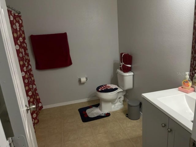 full bath with toilet, tile patterned floors, baseboards, and vanity
