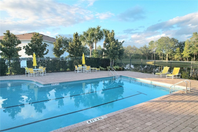 view of swimming pool featuring a patio and a water view