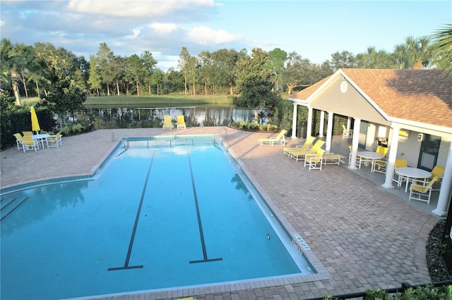 community pool featuring a water view, a patio area, and fence