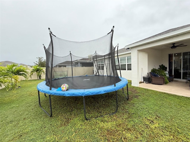 view of yard featuring ceiling fan, a patio, and a trampoline