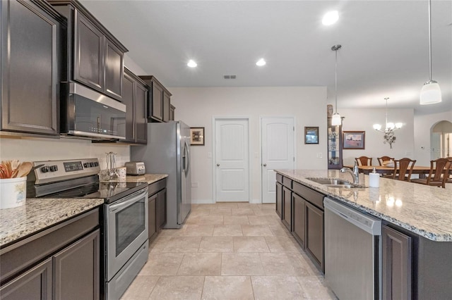 kitchen with dark brown cabinetry, an island with sink, sink, decorative light fixtures, and appliances with stainless steel finishes