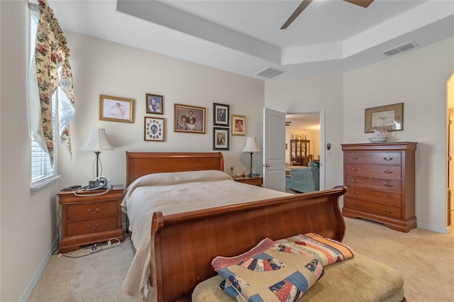 bedroom with a raised ceiling, light carpet, and ceiling fan