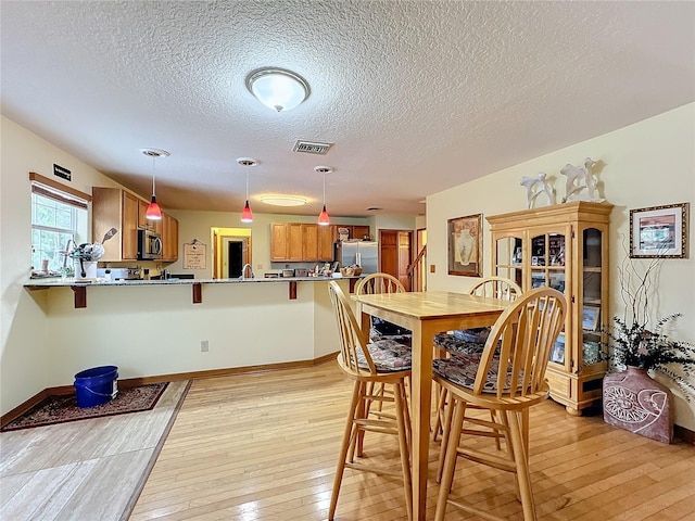 dining room featuring a textured ceiling and light hardwood / wood-style flooring