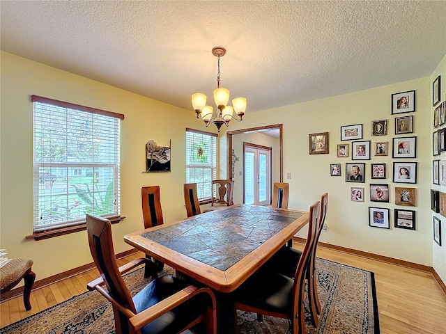 dining space with light hardwood / wood-style flooring, a textured ceiling, and a healthy amount of sunlight