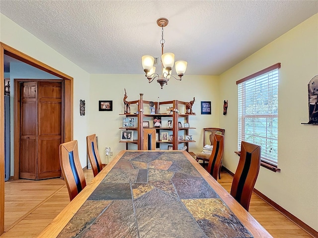 dining room featuring an inviting chandelier, light wood-type flooring, and a textured ceiling