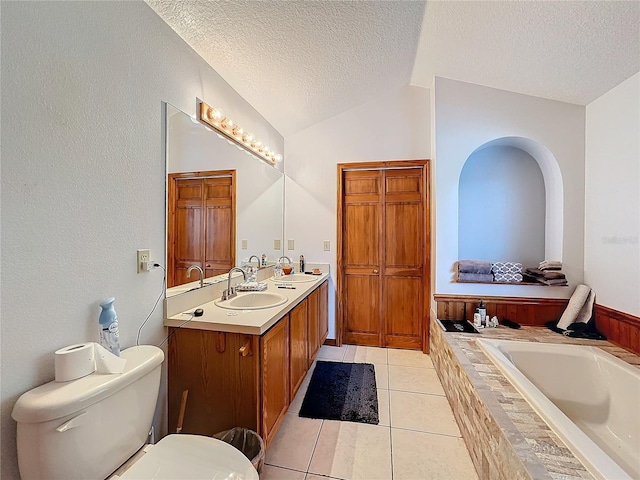 bathroom featuring vanity, tiled tub, vaulted ceiling, toilet, and a textured ceiling