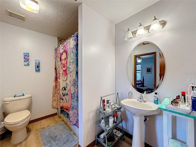 bathroom with wood-type flooring, a textured ceiling, walk in shower, and toilet