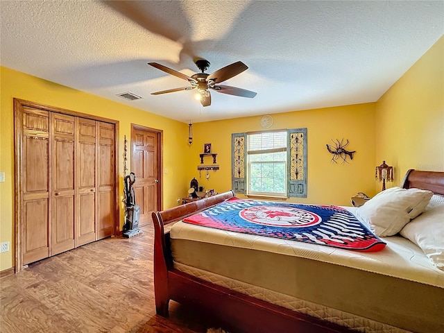 bedroom with ceiling fan, a textured ceiling, a closet, and light hardwood / wood-style floors