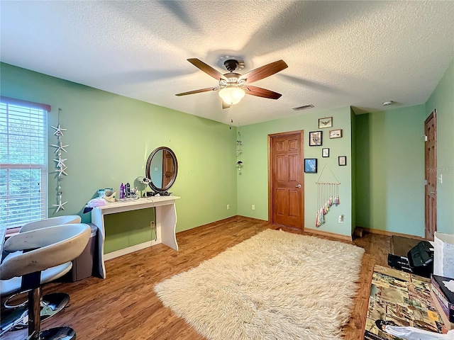 interior space with ceiling fan, wood-type flooring, and a textured ceiling