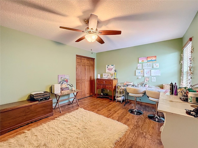 office with a textured ceiling, ceiling fan, and light hardwood / wood-style flooring