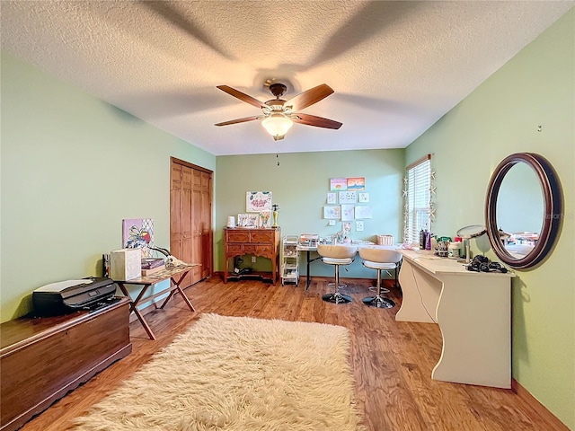 office space featuring ceiling fan, light wood-type flooring, and a textured ceiling