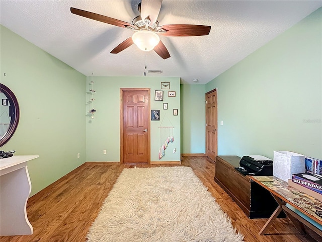 bedroom with a textured ceiling, ceiling fan, and light hardwood / wood-style flooring