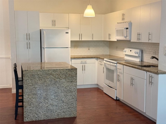 kitchen with hanging light fixtures, dark wood-type flooring, white appliances, and white cabinetry