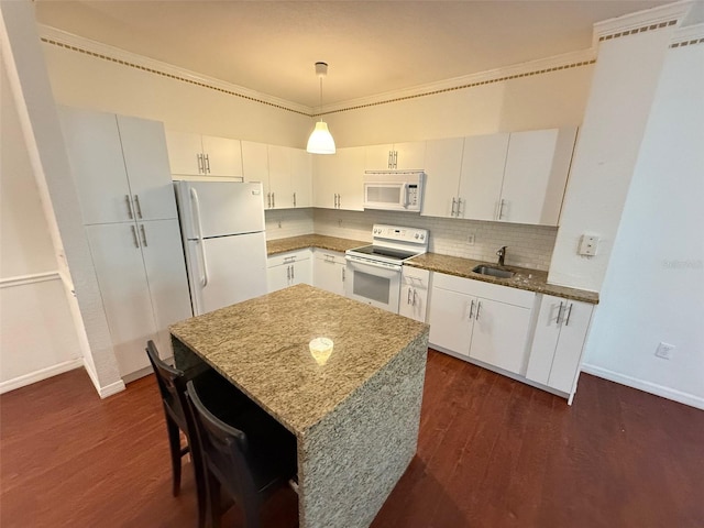 kitchen with dark wood-type flooring, white appliances, decorative light fixtures, and white cabinetry