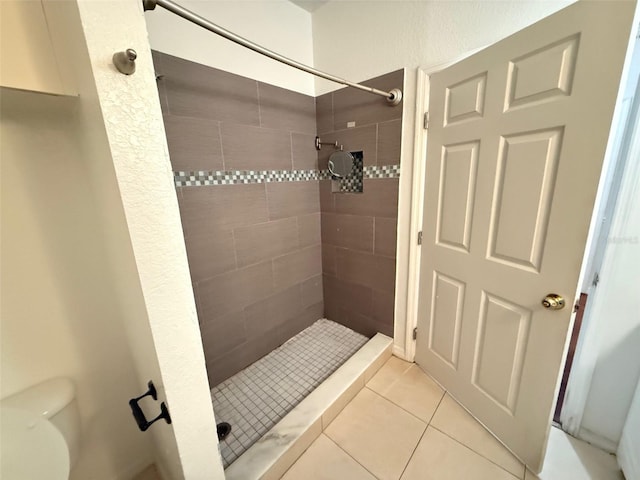 bathroom with tile patterned flooring, tiled shower, and toilet