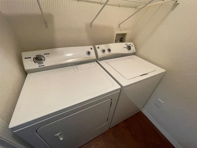 washroom with washing machine and clothes dryer and dark hardwood / wood-style flooring