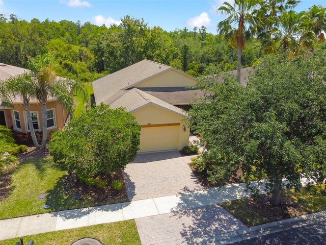 196 Ventana Dr, Kissimmee, FL 34759 - view of front of property with decorative driveway, stucco siding, a garage, and a view of trees