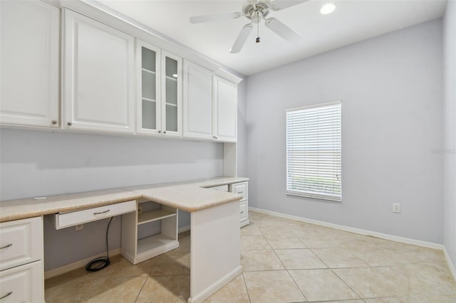 unfurnished office with built in desk, light tile patterned flooring, and ceiling fan