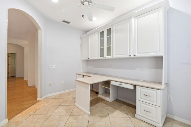 unfurnished office featuring light hardwood / wood-style floors, built in desk, and ceiling fan