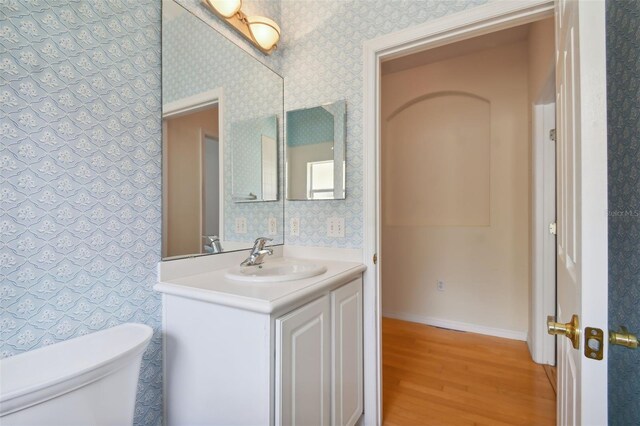 196 Ventana Dr, Kissimmee, FL 34759 - bathroom featuring toilet, wood finished floors, vanity, baseboards, and wallpapered walls