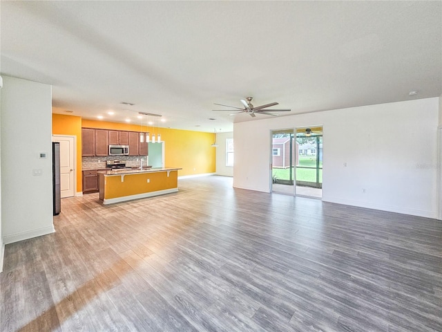 unfurnished living room featuring ceiling fan, sink, and wood-type flooring