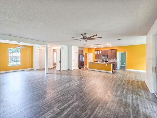 unfurnished living room with ceiling fan, dark hardwood / wood-style floors, and a textured ceiling