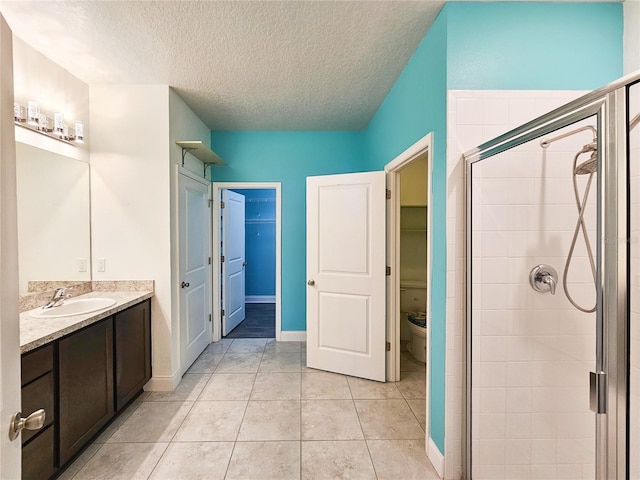 bathroom featuring tile patterned flooring, toilet, an enclosed shower, vanity, and a textured ceiling