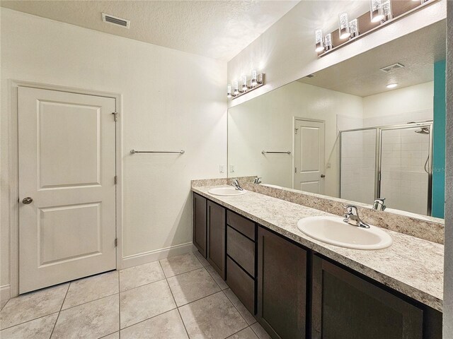 bathroom with tile patterned flooring, a shower with door, vanity, and a textured ceiling