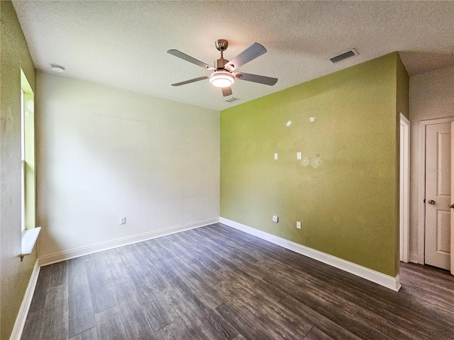 spare room featuring ceiling fan, dark wood-type flooring, and a textured ceiling