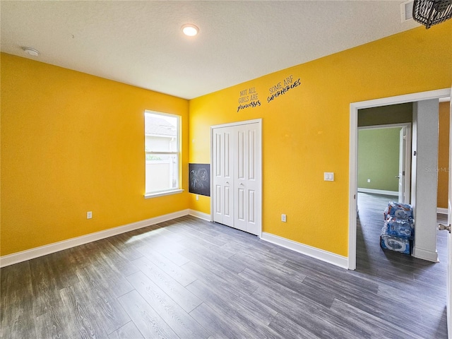 unfurnished bedroom with a closet and dark hardwood / wood-style flooring